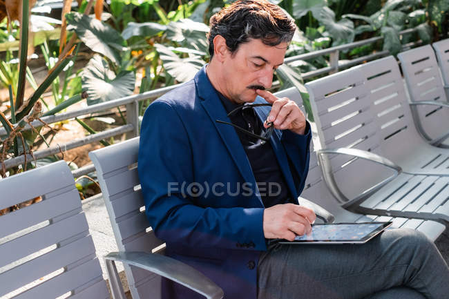 Homem bonito envelhecido usando tablet digital ao ar livre — Fotografia de Stock