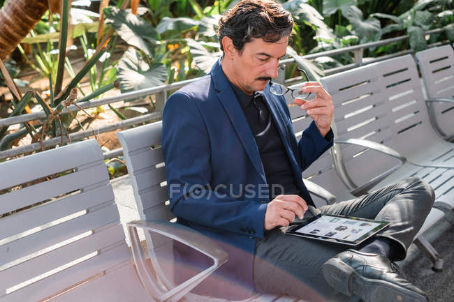 Aged handsome man using digital tablet outdoors — Stock Photo