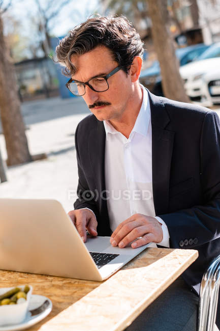 Homem idoso usando gadget enquanto relaxa no café — Fotografia de Stock