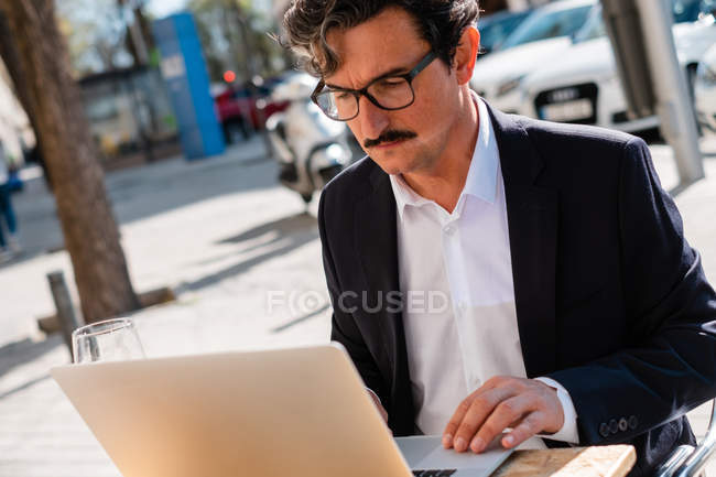 Elderly man using gadget while relaxing at cafe — Stock Photo