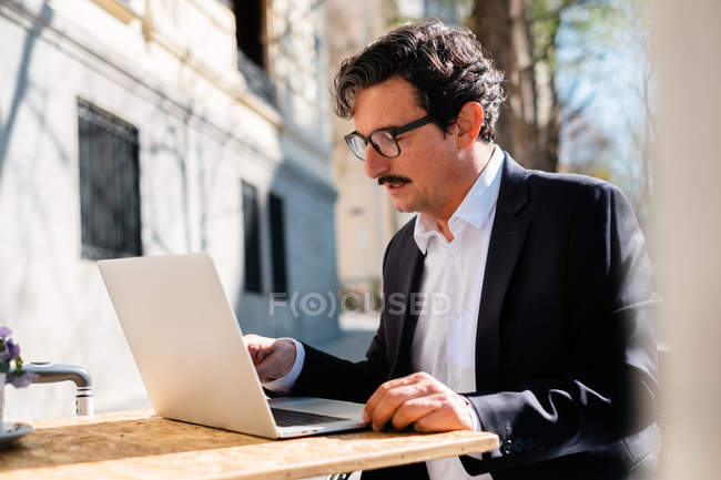 Elderly man using gadget while relaxing at cafe — Stock Photo