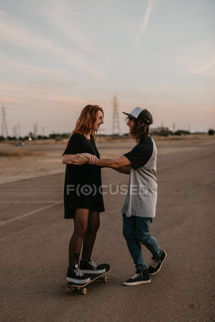 Rire adolescent guy et fille apprendre à patiner avoir amusant sur rue — Photo de stock