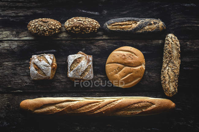 Плоская кладка из золота ассортимент домашнего хлеба на темном деревянном фоне — стоковое фото