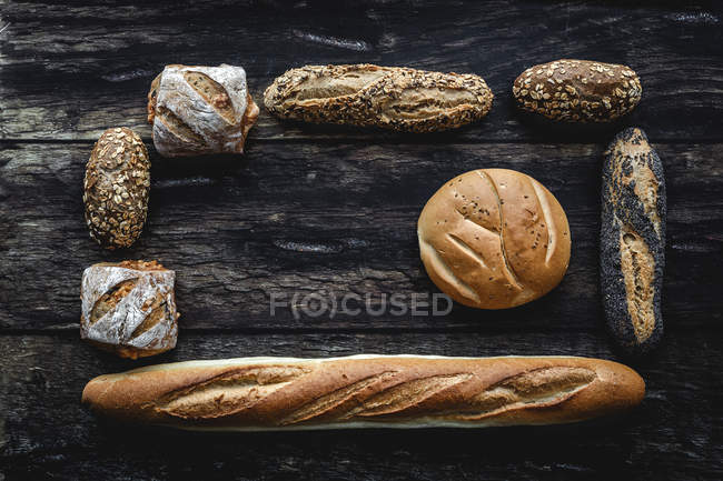 Плоский шар золотого асортименту домашнього хліба на темному дерев'яному фоні — стокове фото