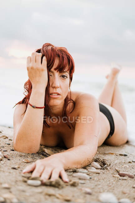 Mujer desnuda acostada cerca de las olas del mar - foto de stock