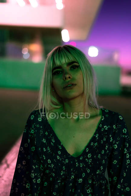 Attraktive selbstbewusste blonde Frau, die interessiert in die Kamera blickt, während sie im Morgengrauen allein auf der Straße steht — Stockfoto
