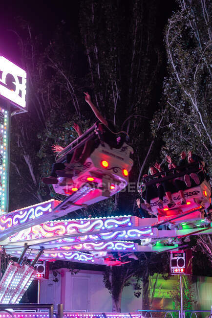 People on illuminated amusement ride in park — Stock Photo