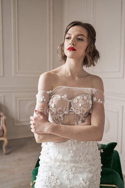 Magnifique jeune mariée coûteuse en robe de dentelle blanche regardant loin et réfléchissant — Photo de stock