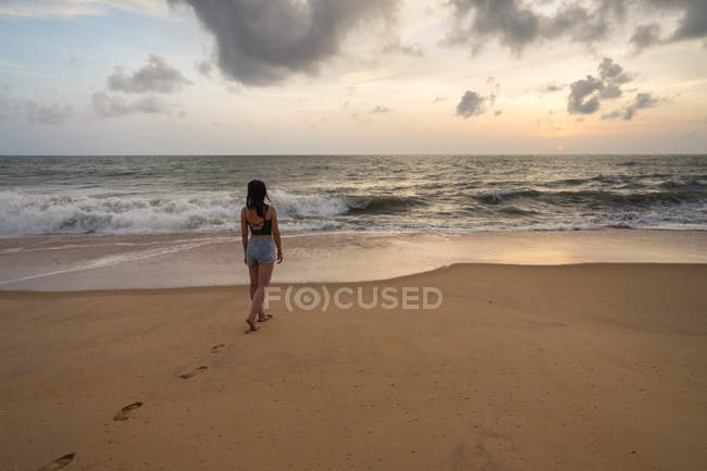 Mujer en ropa de playa caminando sobre arena descalza - foto de stock