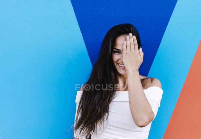 Jovem elegante encostada a uma parede enquanto esconde o rosto com a mão — Fotografia de Stock