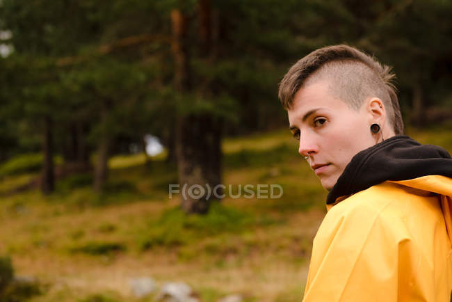 Mujer en impermeable amarillo caminando en el bosque - foto de stock