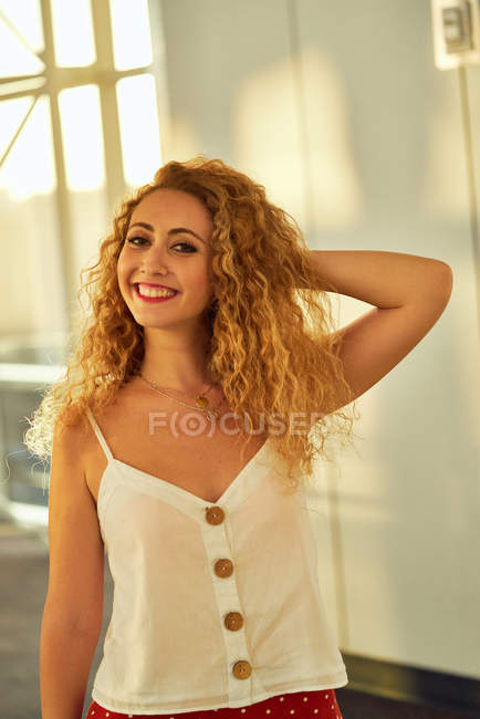 Curly charming woman smiling away while walking in light glassy room of airport in Texas — Stock Photo