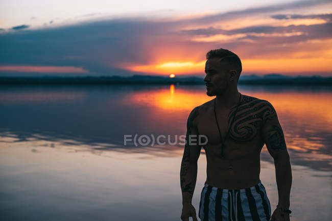 Silhouette dell'uomo in piedi mentre si gode il cielo del tramonto sulla spiaggia calma del lago rosa in Spagna — Foto stock