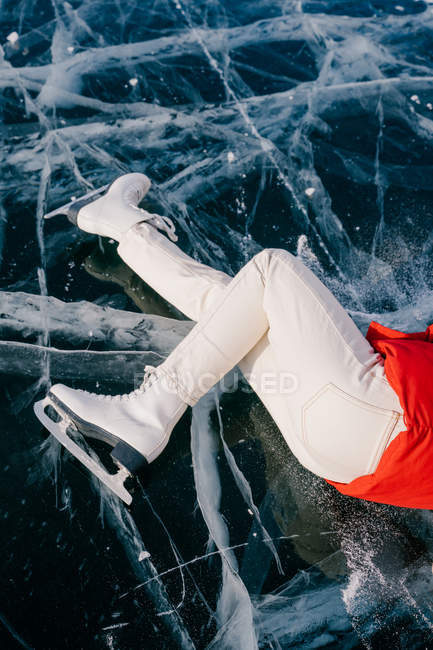 Abgeschnittenes Bild einer Frau auf Schlittschuhen, die auf Eis liegt — Stockfoto