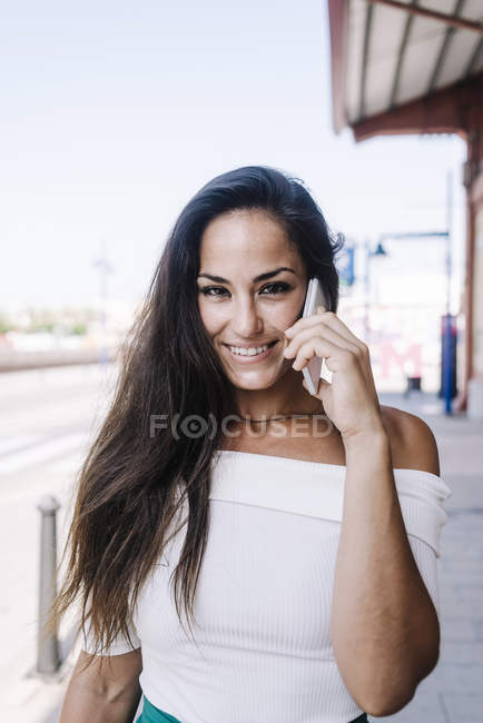 Beautiful woman talking on mobile phone at street — Stock Photo