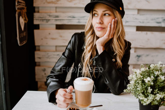 Longo cabelo na moda bela mulher loira bebendo de um copo de delicioso café espumoso — Fotografia de Stock