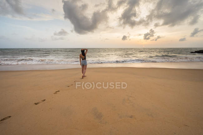 Жінка на пляжі ходить по піску босоніж. — стокове фото