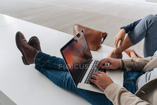 Imagem cortada de empresários navegando laptop juntos enquanto sentado fora do edifício moderno na rua da cidade — Fotografia de Stock