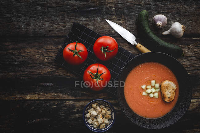 Homemade typical Spanish gazpacho from above. Salmorejo. Tomato soup with cucumber; Green pepper, bread and olive oil on dark wood background. Spanish food. Flat lay. — Stock Photo