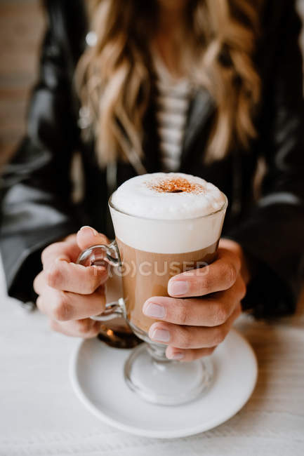 Cropped image of trendy woman holding glass of delicious foamy coffee — Stock Photo