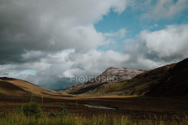 Paisaje del valle otoñal situado entre colinas con carretera rural y líneas eléctricas - foto de stock