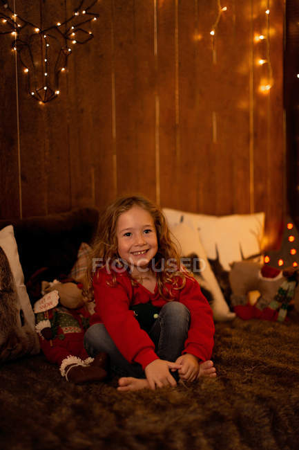 Adorable little girl sitting in a room full of Christmas decoration and looking away — Stock Photo