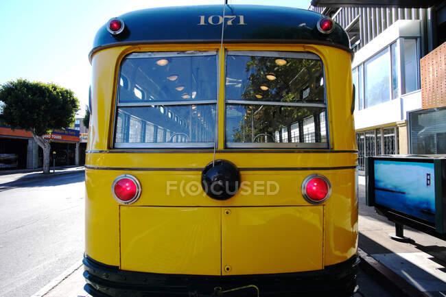 Зовнішній вигляд блискучого жовтого автобуса, припаркованого біля тротуару в сонячний день на вулиці міста — стокове фото