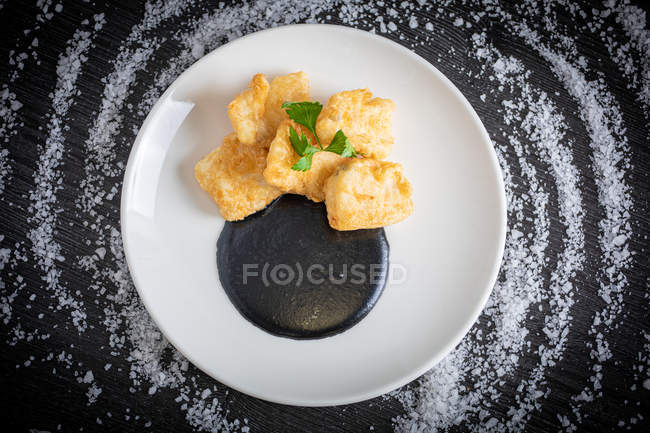 Hake breaded with squid cream in plate — Stock Photo