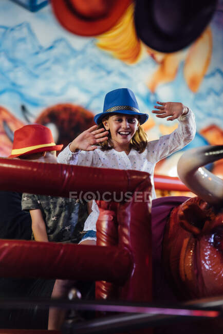 Cheerful girl riding mechanical bull — Stock Photo
