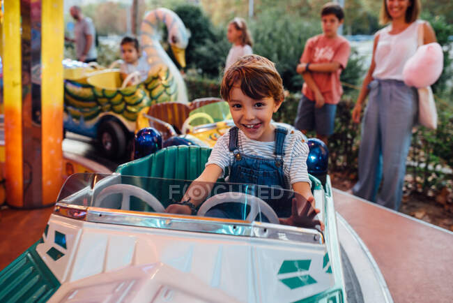 Joyeux garçon chevauchant carrousel sur le terrain de foire — Photo de stock