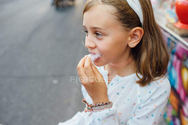 Весела дівчина їсть бавовняні цукерки на вулиці — стокове фото