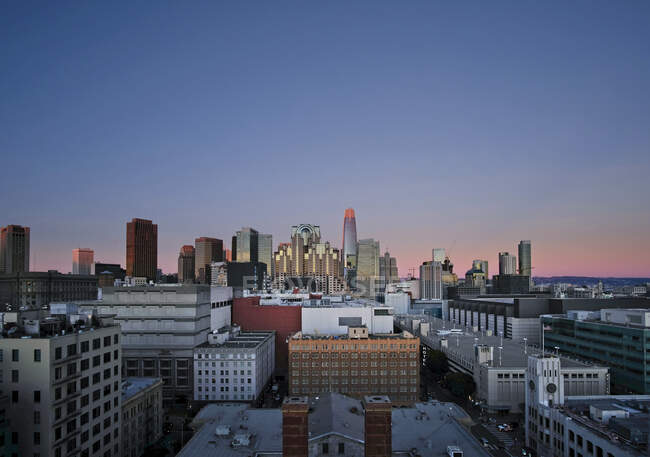 Vista drone da cidade metropolitana iluminada com arranha-céus contra céu azul escuro sem nuvens à noite — Fotografia de Stock