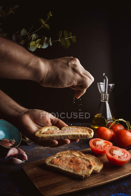 Hände von Personen, die Salz auf Toastbrot gießen — Stockfoto