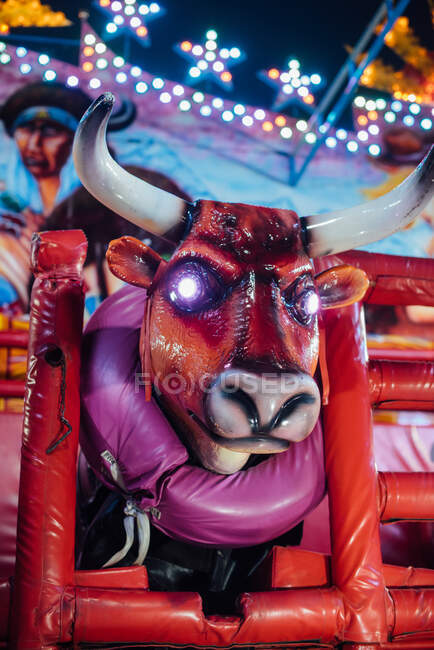 Нижній кут сучасного механічного бика з сяючими очима, розташовані на ярмарку ввечері в місті. — стокове фото