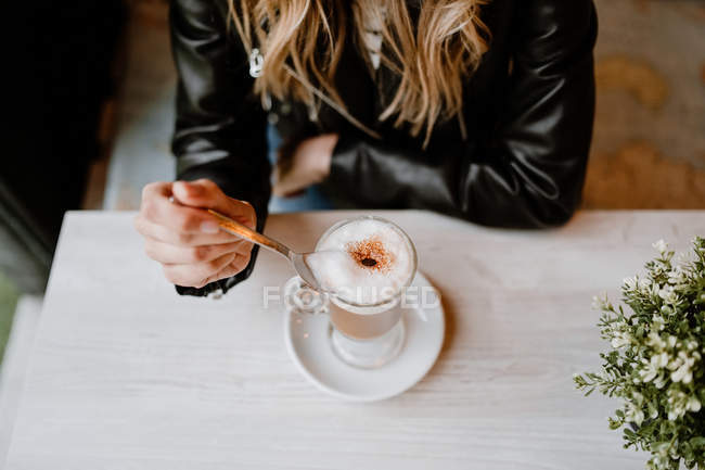 Cropped image of woman drinking from a glass of delicious foamy coffee — Stock Photo
