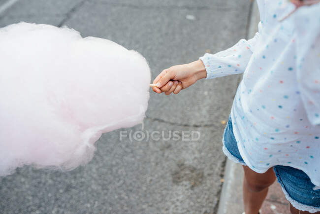 Веселая девушка ест сахарную вату на улице — стоковое фото