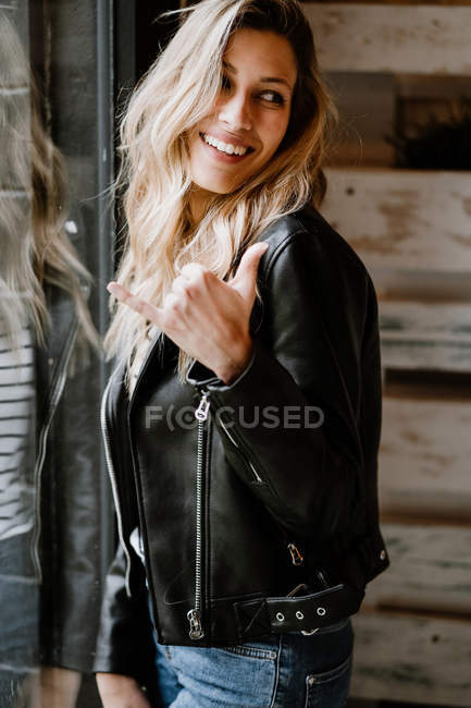 Mulher alegre de cabelos longos na moda em jaqueta de couro e boné olhando para longe — Fotografia de Stock
