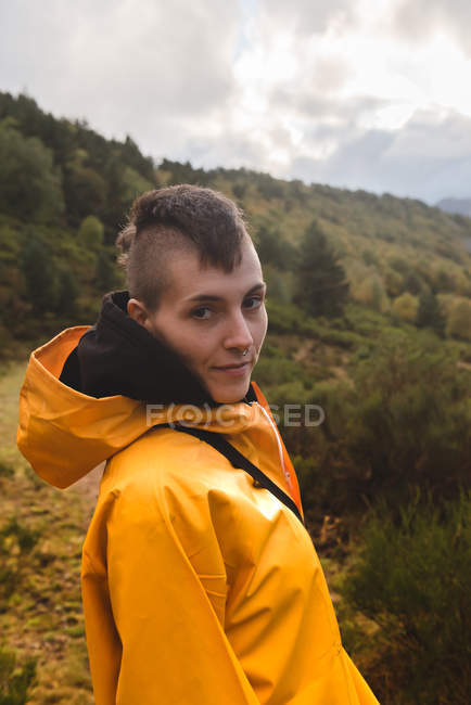 Attractive woman in yellow raincoat walking in forest — Stock Photo
