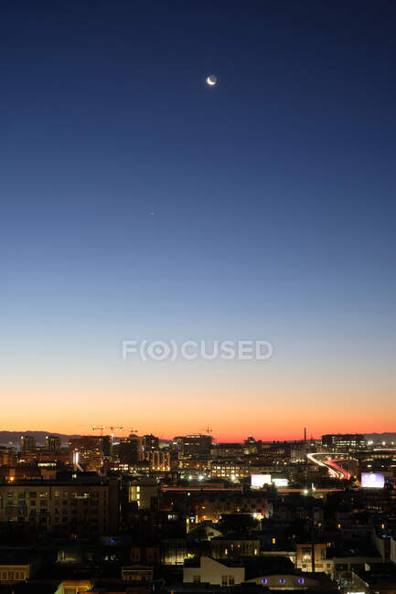 Arranha-céus com iluminação colorida localizada contra o céu escuro do pôr do sol na metrópole — Fotografia de Stock