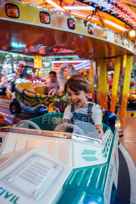 Rapaz feliz montando carrossel no parque de diversões — Fotografia de Stock