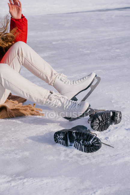 Обрізане зображення жінки, що сидить на снігу і змінює чоботи — стокове фото