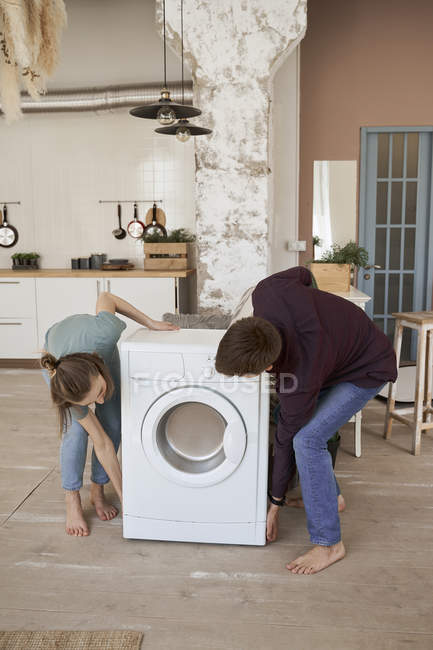 Side view of barefoot content man and woman carrying washing machine while moving to new house — Stock Photo
