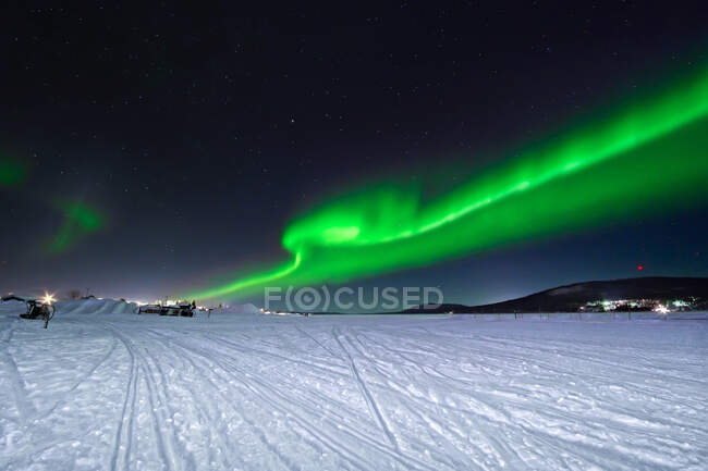 Des aurores boréales vertes brillent sur le ciel nocturne au-dessus des conifères et du sol enneigé en hiver dans la nature — Photo de stock