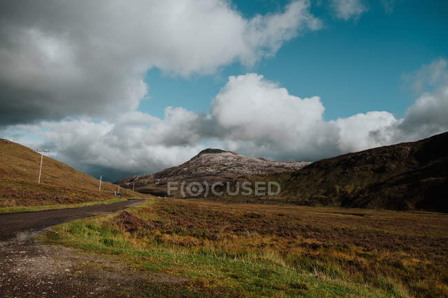 Paisaje del valle otoñal situado entre colinas con rieles rurales y líneas eléctricas - foto de stock