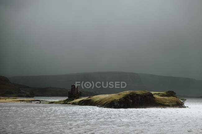 Paesaggio di piccola isola vicino alla costa della Scozia durante il giorno tempestoso con colline nebbiose e rovine del castello — Foto stock