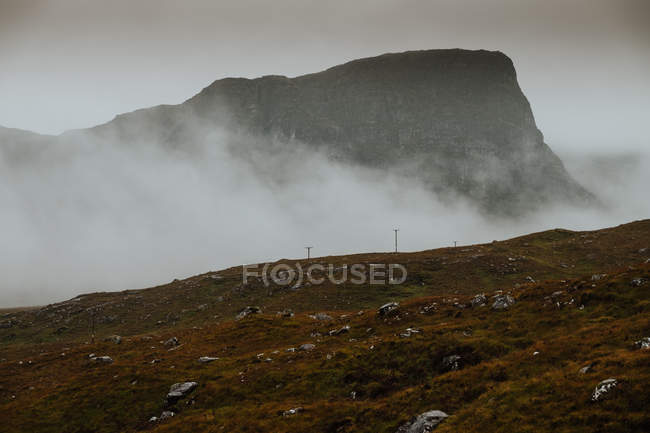 Дикие пейзажи скалистых холмов, покрытых густым туманом в Шотландии — стоковое фото