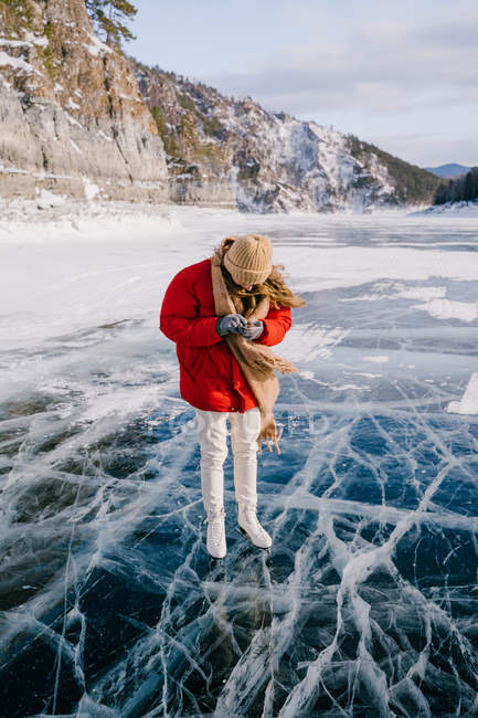 Frau auf Schlittschuhen steht auf Eis und telefoniert — Stockfoto