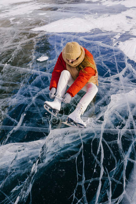 Frau sitzt auf gefrorenem Fluss und bindet Schnürsenkel — Stockfoto