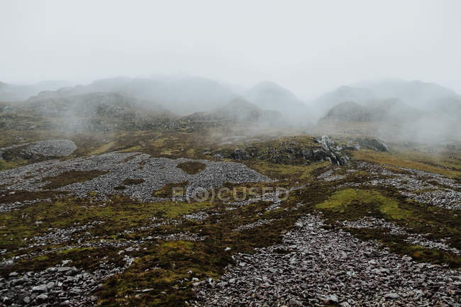 Paysage sauvage de collines rocheuses couvertes par une épaisse brume en Écosse — Photo de stock