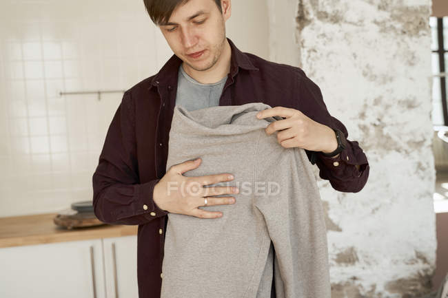 Man folding soft gray sweater at home — Stock Photo